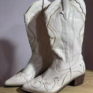 Step into the season with the ultimate statement piece. Our White Vintage Western Boots blend the rugged spirit of the frontier with high-fashion elegance. Featuring intricate tonal embroidery and a sophisticated pointed toe, these knee-high boots are designed to turn heads at weddings, festivals, or on a casual autumn stroll.
