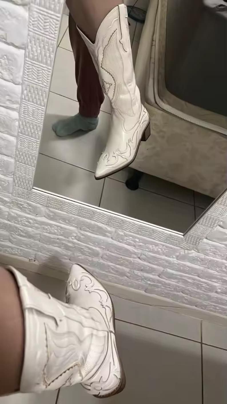 Step into the season with the ultimate statement piece. Our White Vintage Western Boots blend the rugged spirit of the frontier with high-fashion elegance. Featuring intricate tonal embroidery and a sophisticated pointed toe, these knee-high boots are designed to turn heads at weddings, festivals, or on a casual autumn stroll.