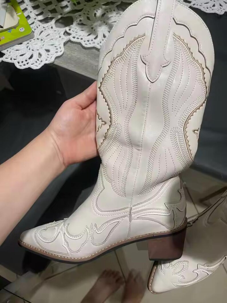 Step into the season with the ultimate statement piece. Our White Vintage Western Boots blend the rugged spirit of the frontier with high-fashion elegance. Featuring intricate tonal embroidery and a sophisticated pointed toe, these knee-high boots are designed to turn heads at weddings, festivals, or on a casual autumn stroll.