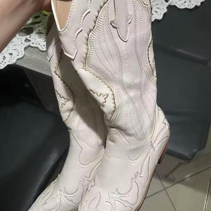 Step into the season with the ultimate statement piece. Our White Vintage Western Boots blend the rugged spirit of the frontier with high-fashion elegance. Featuring intricate tonal embroidery and a sophisticated pointed toe, these knee-high boots are designed to turn heads at weddings, festivals, or on a casual autumn stroll.