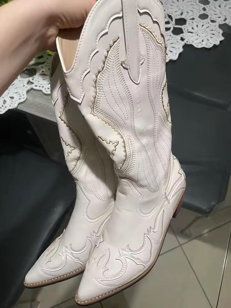 Step into the season with the ultimate statement piece. Our White Vintage Western Boots blend the rugged spirit of the frontier with high-fashion elegance. Featuring intricate tonal embroidery and a sophisticated pointed toe, these knee-high boots are designed to turn heads at weddings, festivals, or on a casual autumn stroll.