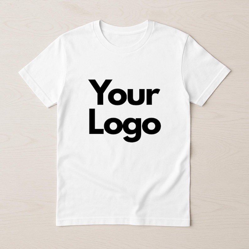 May include: White t-shirt with the text "Your Logo" in bold black letters. The shirt has short sleeves and a crew neck. The design is centered on the front of the shirt.