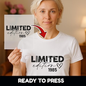 Könnte beinhalten: Weißes T-Shirt mit dem schwarzen Text "LIMITED edition 1985" und einem Herzsymbol. Die Worte "READY TO PRESS" stehen unten im Bild auf einem schwarzen Banner. Das Design befindet sich auch auf einer transparenten Folie.