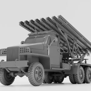 May include: A gray model of a military truck with multiple rocket launchers mounted on the back. The truck has large tires and a detailed front grill. The rocket launchers are angled upwards.