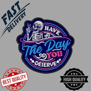 Könnte beinhalten: Gestickter Aufnäher mit einem Skelett, das ein Friedenszeichen zeigt, umgeben von dem Text "Have The Day You Deserve". Das Design verwendet Blau, Rosa und Weiß auf einem marineblauen Hintergrund. Der Aufnäher hat eine einzigartige Form.