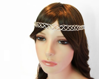 Puede incluir: Diadema de alambre plateado con un diseño trenzado. La diadema se lleva en un maniquí con cabello castaño.