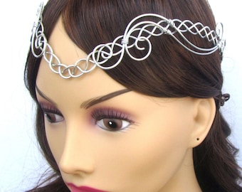 May include: Silver wire headband with a delicate, intricate design. The headband is worn on a mannequin with brown hair.