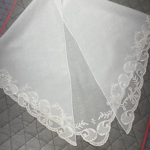 May include: White cotton handkerchief with delicate embroidered floral lace trim.