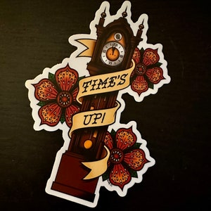 May include: A sticker featuring a vintage-style clock with the text "TIME'S UP!" and floral accents. The clock is brown with a white face and black Roman numerals. The flowers are orange and red with a black center.