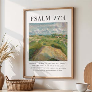 May include: A framed print featuring the text "PSALM 27:4" above a landscape painting of rolling green hills under a cloudy sky. The print includes a quote about seeking the Lord. The frame is made of light brown wood.