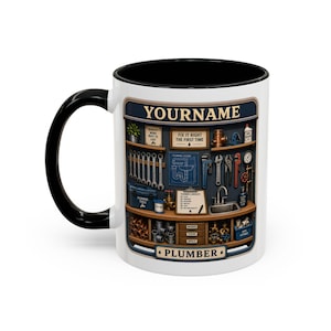 Peut inclure: Mug en céramique blanche avec une anse et un intérieur noirs. La tasse présente une illustration détaillée d'une boîte à outils et d'outils de plombier, avec le texte "YOURNAME" et "PLUMBER". La conception comprend des clés, des tuyaux et un plan.