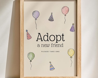 Puede incluir: Un cartel enmarcado con las palabras "Adopt a new friend" y "Please take one". El cartel presenta ilustraciones de globos y sombreros de fiesta en varios colores, incluyendo morado, rosa, verde y amarillo. El marco es de madera clara.