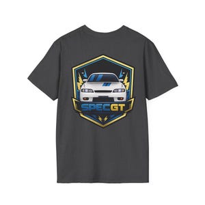 以下が含まれることがあります： 背面にグラフィックがプリントされたダークグレーのTシャツ。デザインは、青と金の盾のエンブレムの中に白いスポーツカーが描かれています。盾の下部には青い文字で「SPEC GT」と記されており、黄色の稲妻のアクセントが添えられています。