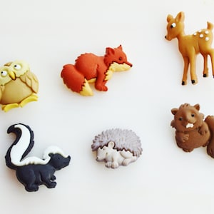 May include: A collection of colorful woodland animal figurines, including an owl, fox, deer, skunk, hedgehog, and beaver. The figurines are made of a smooth material and are set against a white background. Each animal is approximately 1-2 inches in size.