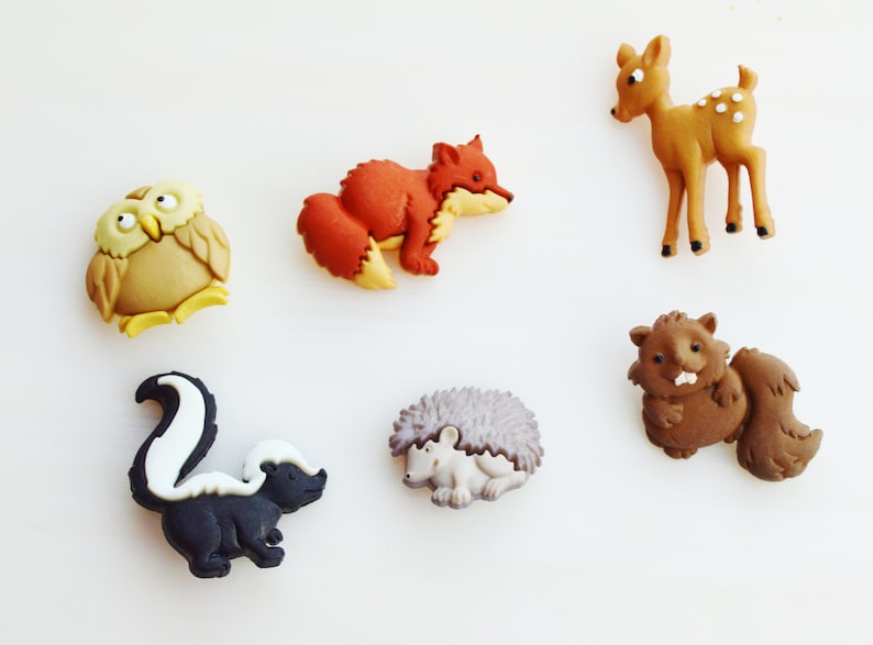 May include: A collection of colorful woodland animal figurines, including an owl, fox, deer, skunk, hedgehog, and beaver. The figurines are made of a smooth material and are set against a white background. Each animal is approximately 1-2 inches in size.
