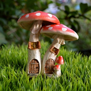 May include: A whimsical fairy garden mushroom house with a red cap dotted with white spots. The mushroom house has two wooden doors, small windows, and is surrounded by green grass. A miniature mushroom family.