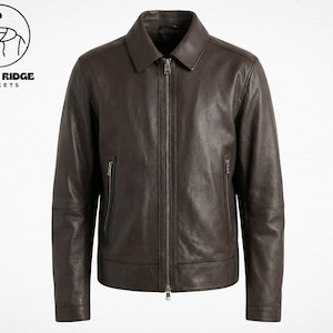 Peut inclure: Veste en cuir marron foncé avec col et fermeture éclair. La veste a deux poches latérales zippées. Le logo "RETRO RIDGE JACKETS" est dans le coin supérieur gauche.