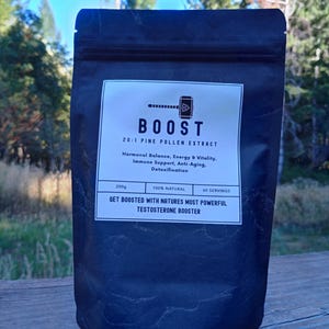 Puede incluir: Una bolsa negra de "BOOST" Extracto de Polen de Pino 20:1. La etiqueta blanca incluye texto sobre equilibrio hormonal, energía, vitalidad, apoyo inmunológico, antienvejecimiento y desintoxicación. La bolsa contiene 200g y 60 porciones.