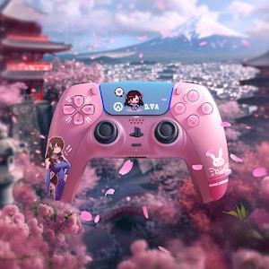 May include: A pink video game controller with a D.Va theme. The controller features a blue accent with pixel art and the text "D.VA". The design includes anime-style graphics and a bunny logo, set against a Japanese landscape.