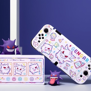 Può includere: Custodia bianca per Nintendo Switch con un design Gengar colorato. La custodia presenta un personaggio dei cartoni animati Gengar, stelle e altre grafiche. È visibile anche una scatola abbinata con la scritta "Colorful" e un display digitale, insieme a due statuette di Gengar.