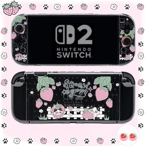 Op de afbeelding: Een zwarte Nintendo Switch-console met een aardbeienthema. De console heeft roze aardbeien, groene bladeren en de tekst "Strawberry". Het ontwerp bevat pootafdrukken en bloemaccenten. Het Nintendo Switch-logo is zichtbaar.