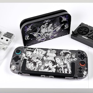 Op de afbeelding: Nintendo Switch console, hoes en controller met een zwart-wit manga-stijl grafisch ontwerp. De console heeft de tekst "NANA" en "BLACK STONES". De hoes en controller hebben bijpassende ontwerpen.