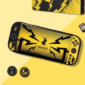 Op de afbeelding: Een gele en zwarte Nintendo Switch-console met een Pikachu-thema. De console heeft een gele achtergrond met zwarte bliksemgraphics en een Pikachu-silhouet. De tekst "NINTENDO SWITCH 2" is zichtbaar. Twee zwarte thumb grips zijn ook inbegrepen.