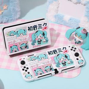 Peut inclure: Une coque et une manette blanches pour Nintendo Switch avec un design de personnage de dessin animé dans les tons de bleu, rose et noir. Le boîtier et la manette comportent du texte japonais et une figurine assortie.