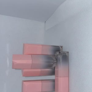 Puede incluir: Una colecci&oacute;n de labiales rosas y transparentes. Los labiales tienen un dise&ntilde;o degradado, que pasa del rosa al transparente. Los tubos de l&aacute;piz labial est&aacute;n dispuestos verticalmente, mostrando su forma y color.