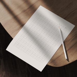 May include: A white pencil rests on a grid-lined paper, positioned on a wooden surface. The paper has a light gray grid pattern. The scene is illuminated by natural light, creating shadows.