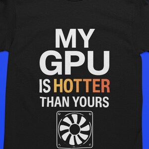 May include: Black t-shirt with the text "MY GPU IS HOTTER THAN YOURS" in white and orange. A graphic of a computer fan is below the text. The shirt is on a blue background.