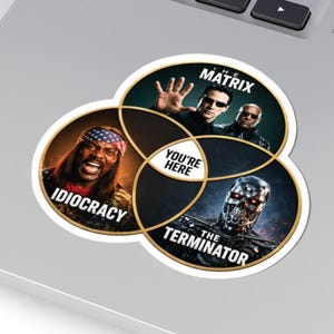 May include: A circular sticker featuring a Venn diagram with three overlapping sections. The sections display images from the films The Matrix, Idiocracy, and The Terminator. The central intersection contains the text "YOU'RE HERE" in black letters.
