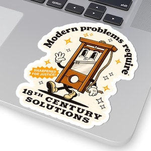 Puede incluir: Una pegatina troquelada con una guillotina de dibujos animados sonriente. La pegatina dice: "Los problemas modernos requieren soluciones del siglo XVIII" y "¡Afilado para la justicia!" en un estilo vintage.