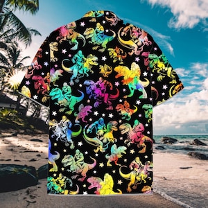 May include: Black button-up shirt with a vibrant, all-over print featuring colorful dinosaurs ridden by muscular figures. White stars are scattered across the design. The shirt has short sleeves and a classic collar, perfect for a casual look.