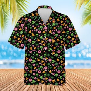 Op de afbeelding: Zwart overhemd met korte mouwen en een herhaald patroon van groene alienkoppen, roze donuts, pizzapunten en groene cannabisbladeren. Het overhemd heeft een klassieke kraag en een relaxte pasvorm.