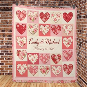 May include: A patchwork quilt with a repeating pattern of pink and red hearts. Some hearts are decorated with floral patterns, others with polka dots. The names "Emily & Michael" and the date "February 14, 2015" are displayed in the centre.