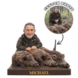Op de afbeelding: Een op maat gemaakte figuur met een man met een baard, geposeerd met drie wilde zwijnen. De figuur bevat een miniatuur geweer en een foto in een cirkel met het label "CUSTOM PHOTO". De bruine basis heeft de naam "MICHAEL".