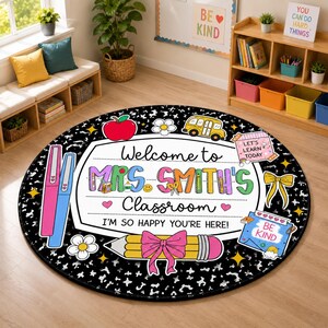 May include: A round black and white speckled classroom rug featuring a central white label with the text Welcome to Mrs. Smith's Classroom I'm so happy you're here. The design includes a red apple, yellow school bus, pencil with a pink bow, and notes.
