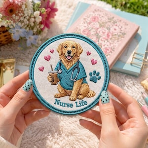Può includere: Una toppa ricamata circolare raffigurante un golden retriever che indossa una casacca medica color verde acqua e uno stetoscopio al collo. Il cane tiene in mano un bicchiere di caffè, circondato da cuoricini rosa e un'impronta. Testo Nurse Life.