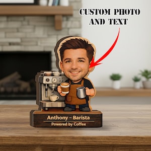 Puede incluir: Figura de barista de madera con una cara sonriente, sosteniendo una taza de café y una jarra de leche. La figura tiene una máquina de café y el texto "Anthony - Barista Powered by Coffee" en la base. La parte superior de la figura tiene el texto "CUSTOM PHOTO AND TEXT".