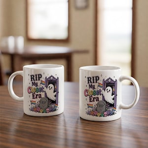 May include: Two white ceramic mugs with a wraparound design. The design features a ghost emerging from a doorway, a tombstone that reads "RIP", and the text "RIP My Closet Era". Rainbow flags and flowers surround the tombstone.