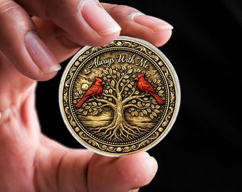 以下が含まれることがあります： 金色の丸いコインで、木と2羽の赤いカージナルバードが描かれています。「Always With Me」という文字が刻まれています。コインは黒い背景に対して2本の指で持たれています。