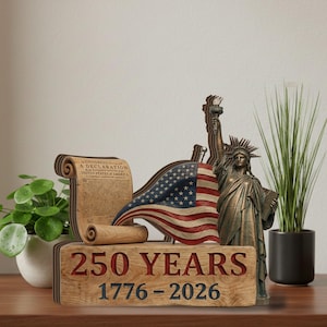 May include: A wooden display featuring the Statue of Liberty, an American flag, and a scroll of the Declaration of Independence. The base reads "250 YEARS 1776-2026" in red and black lettering. A decorative piece celebrating American history.