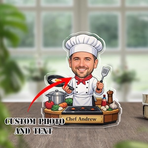 Könnte beinhalten: Klare Acryl-Kochfigur mit einer Cartoon-Illustration eines lächelnden Kochs, der einen Pfannenwender und eine Bratpfanne mit einem Ei hält. Die Basis trägt den Text "CUSTOM PHOTO AND TEXT" und "Chef Andrew".
