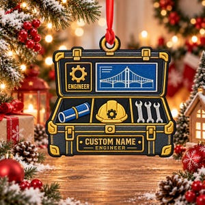 May include: A black and gold toolbox-shaped Christmas ornament featuring a blue blueprint of a bridge, a yellow hard hat, a blue rolled document, and three silver wrenches. The text reads ENGINEER, CUSTOM NAME, and ENGINEER.