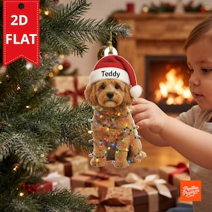 May include: A 2D flat Christmas tree ornament featuring a light brown puppy wearing a red Santa hat with the name Teddy printed on the brim. The puppy is wrapped in a string of colorful, glowing Christmas lights against a white background.