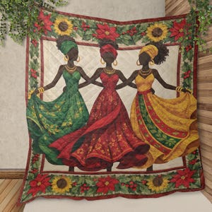 May include: A decorative quilt featuring three silhouetted figures in flowing dresses, holding hands. The figures are in green, red, and yellow dresses. The quilt is bordered with sunflowers, poinsettias, and greenery. The background is a light cream color.