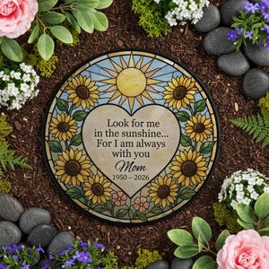 Pode incluir: Uma pedra de jardim redonda e decorativa com um design de vitral. A pedra apresenta uma inscrição em forma de coração: "Look for me in the sunshine... For I am always with you Mom 1950-2026." O design inclui girassóis e um sol.
