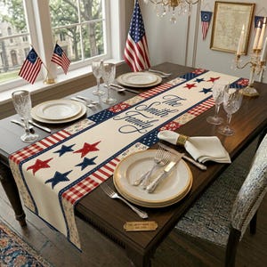Puede incluir: Un camino de mesa rectangular con un diseño patriótico que presenta estrellas y rayas rojas y azules. El panel central dice "The Smith Family". La mesa está puesta con platos, cubiertos y cristalería, creando una escena de comedor festiva.