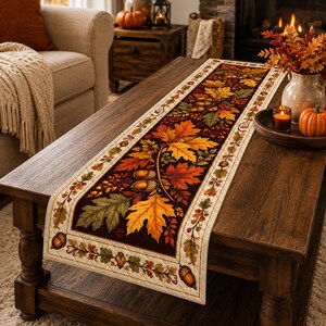 May include: A rectangular table runner featuring a dark brown center panel decorated with vibrant orange, yellow, and green autumn leaves, acorns, and berries. The runner has a cream-colored border with a repeating pattern of small oak leaves.